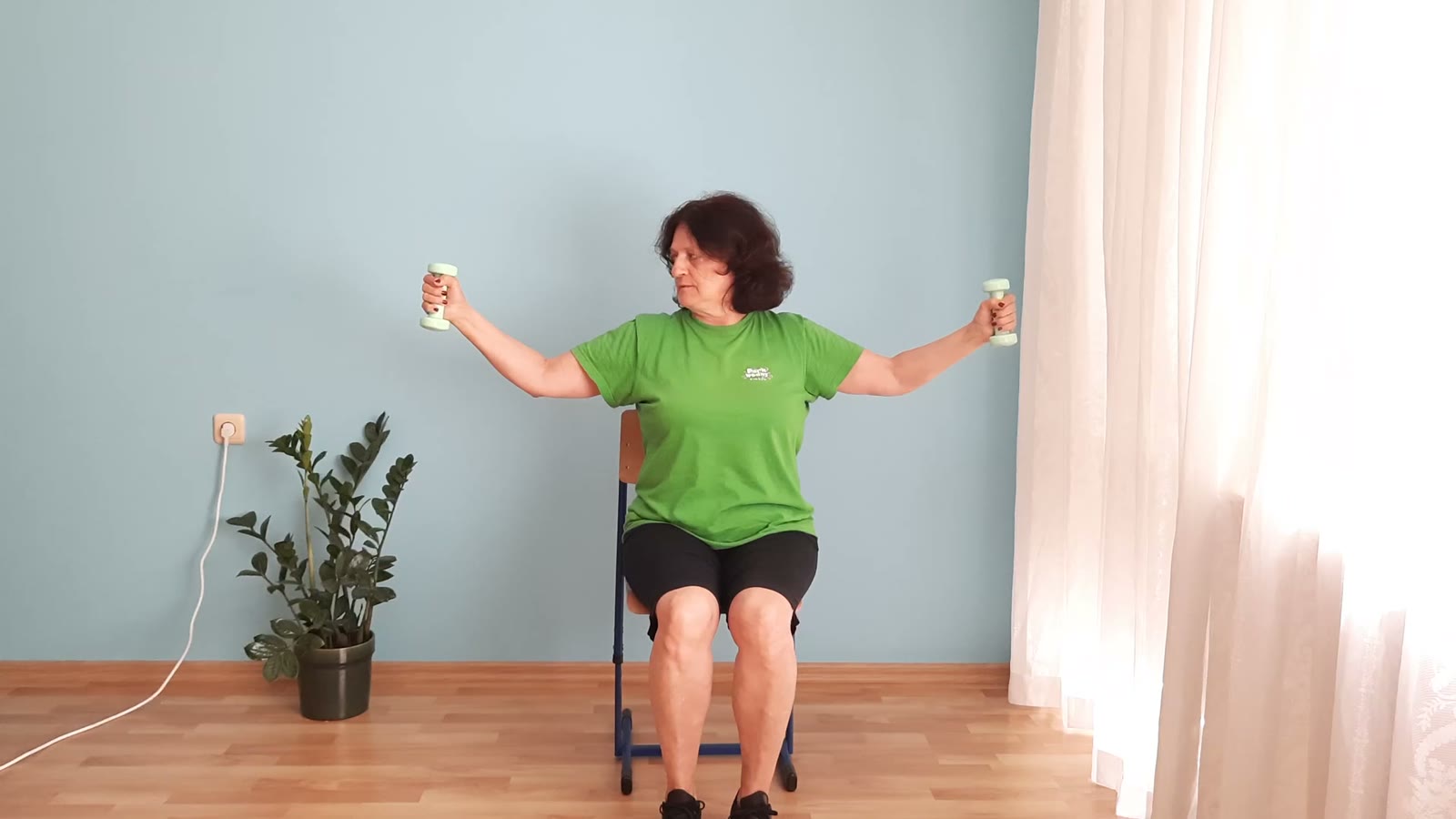 Barbara ćwiczy na krześle z hantlami