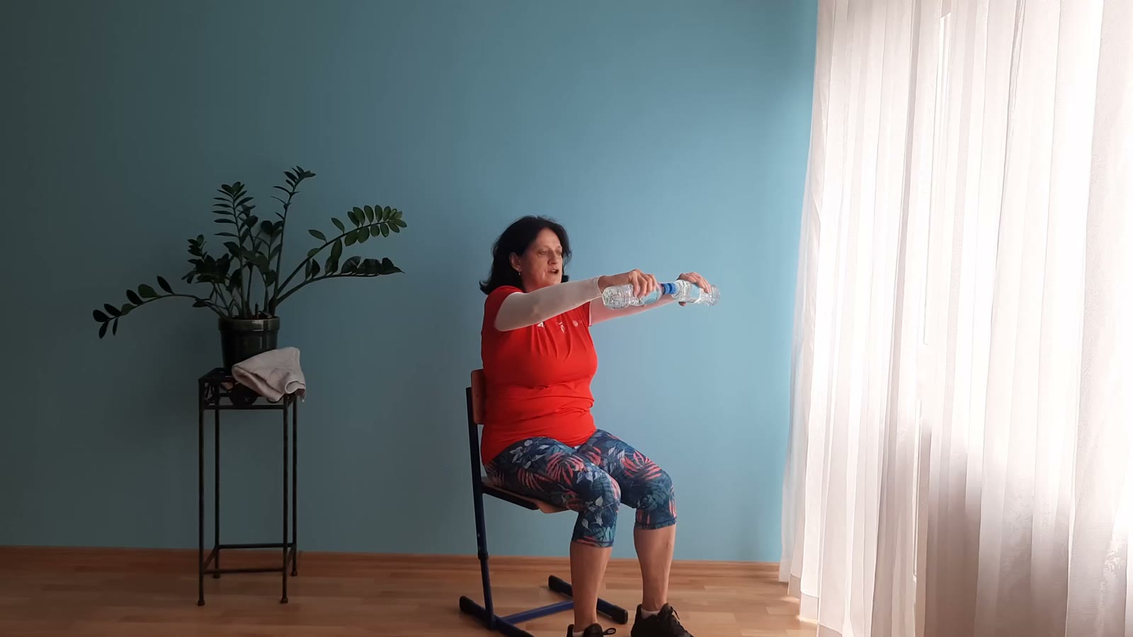 Barbara ćwiczy na krześle z butelką wody